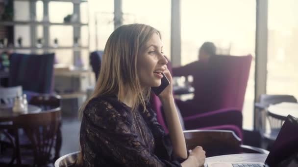 Vackra leende kvinna talande phont. Unga leende kvinna i elegant klänning prata telefon medan du sitter i café. — Stockvideo