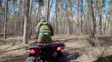 Üzerinde duran ve ile orman iz hareketli pembe Atv çalışan bir genç sporcu, yakın çekim. Genç explorer off-road quad Bisiklet yolunda devam gökyüzü ile ağaçların arasındaki biniyor.