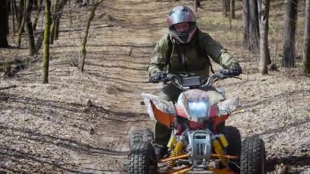 Close up de um homem em equipamento de proteção e capacete operando ATV e se movendo ao longo da estrada de um lado para o outro. Ventilador de turismo extremo andar de quadriciclo no caminho com as pessoas em segundo plano . — Vídeo de Stock