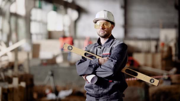 Un ingegnere adulto in un casco tiene tra le mani una livella per misurare il grado di deviazione della superficie dal piano orizzontale — Video Stock