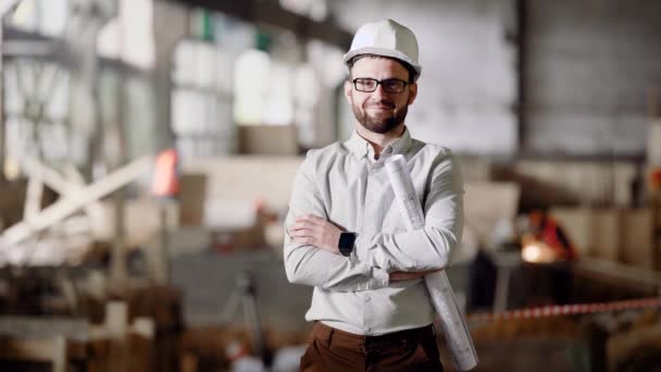 En vuxen arkitekt i en hjälm står på den aktuella byggplatsen, i hans händer ett projekt för modernisering av en övergiven fabrik i staden — Stockvideo