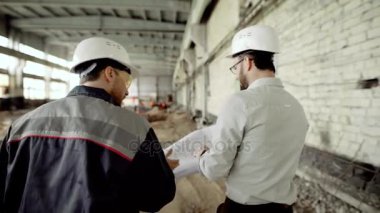 Koruyucu bir kask içinde müşteri iş inşaatçılar inşası nesnede doğrular, insanlar eski fabrika binası ile yürüyüş