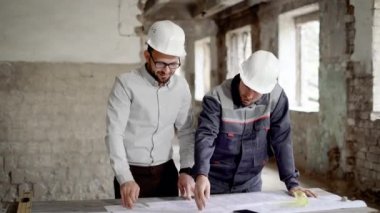 Yetişkin mühendis mimar tarafından tasarlanmış yeni bir inşaat planı için çalışan açıklar, terk edilmiş bir binada insanlar