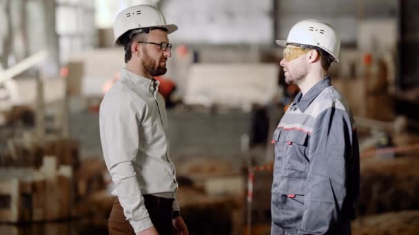 Der Bauarbeiter mit Schutzhelm zeigt dem Geschäftsmann den Arbeitsumfang für die nahe Zukunft, die Männer schütteln Hände und zertrümmern — Stockvideo