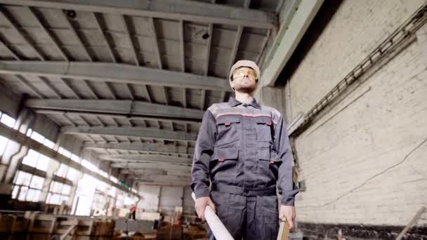 Un trabajador profesional que tiene un espíritu en sus manos está de pie en un edificio donde se está llevando a cabo la renovación global del antiguo edificio. — Vídeo de stock