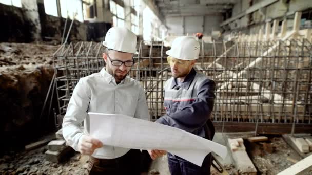 Bir işadamı ve bir profesyonel çalışan eski fabrika binası yükseltme olasılığını belirlemek için çizim bakmak — Stok video