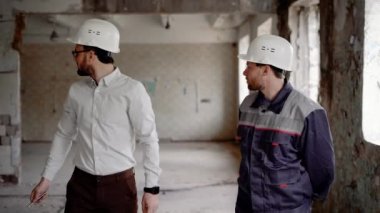 Bir kask kafasına bir işadamı ve bir inşaat baş komiser koruyucu üniformalı yapı gelecekteki yeniden inşası için dikkate
