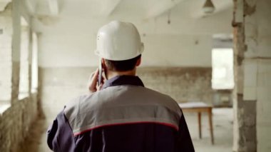 Cep telefonunu bir yetişkin erkek mühendis görüşmeler gider şantiye çizimler için bir tarama nesnenin olduğu