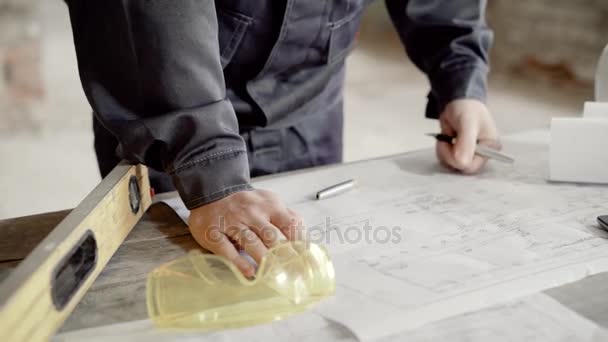 Primo piano colpo di mano mans, che prende appunti nel disegno di costruzione per il caposquadra e costruttori, l'uomo è vestito in uniforme protettiva — Video Stock