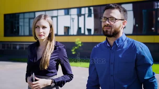 A jovem senhora de negócios está falando com seu gerente da empresa sobre os planos de desenvolvimento futuro da empresa, eles estão andando pelo parque — Vídeo de Stock