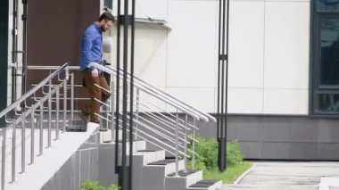 Ağır çekim bir sakallı orta yaşlı bir adam ve bir çanta belgelerle merdivenlerden caddenin için komşu ofis binası için gitmek için gidiyor