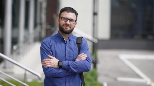 Muž na dvoře úřední budovy. Vedoucí kanceláře na ulici je ve skvělé náladě. Mladý muž se usmívá při pohledu na fotoaparát. — Stock video