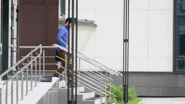 İş Merkezi bahçesinde. Yaprakları office hızı hızlı adam. Genç adam aşağı geliyor.