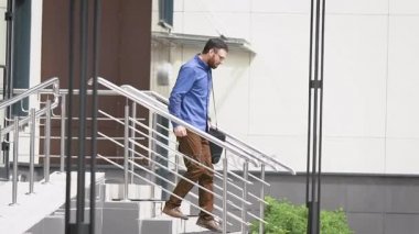 İş Merkezi bahçesinde. Yaprakları office hızı hızlı adam. Genç adam çok neşeli bir merdiven atlar.