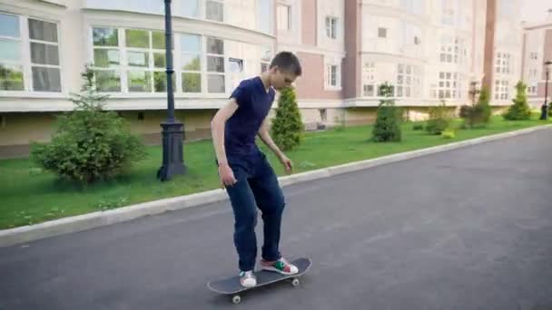 En adult tonåring utför ett enkelt trick på en skateboard under en snabb hastighet, killen studsar och gör en ollie på sin styrelse — Stockvideo