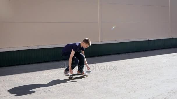 Un joven skateboarder, amante del street style, salta sobre el skateboard para realizar el truco más antiguo - kickflip afuera en verano — Vídeo de stock