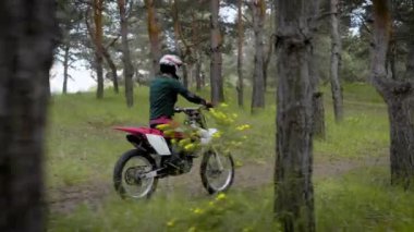 Bir motosikletçi üniforma adlı koruyucu bir kask içinde bir araç üzerinde bir ülke yolunda bir ormanı boyunca biniyor