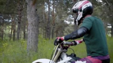 Gündüz daha sık ormanın içinden bir yetişkin motosiklet sürücüsü sürücüler, bir adamın başının üzerinde koruyucu bir kaskı