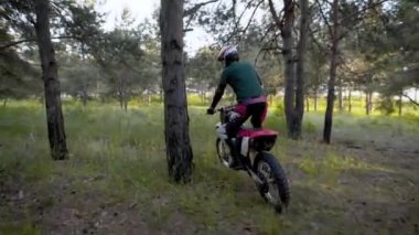 İkinci el motosiklet üzerinde koruyucu bir kask sportif bir erkekte standları, kişi ormanda off-road bir arazi haçlar