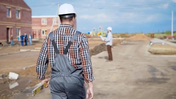 Lugar de construcción. Constructor masculino caminando hacia el arquitecto . — Vídeo de stock