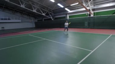 Yetişkin bir adam tenis oynuyor, bir atlet bir raket ile net üzerinden topu atıyor, o sahada ile ortak çalış