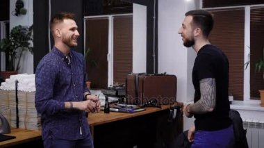 Bir berber dükkanı çalışan bir genç saç stilisti erkekler için ritüel güzellik salonuna gelen samimi bir şekilde, müşteri ile iletişim kurar