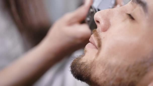 Primer plano de la cara del hombre, a quien se afeita la barba con estilo - una correa de barbilla, esta conexión es una barra lateral con una línea de barba — Vídeos de Stock