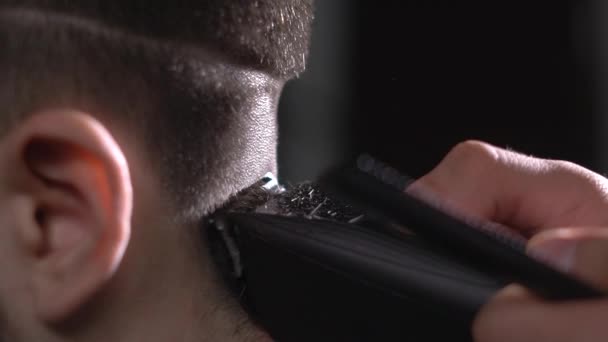 Primer plano del proceso de corte de cabello de un hombre, la máquina de afeitar elimina suavemente el exceso de cabello de la parte posterior del cliente — Vídeos de Stock