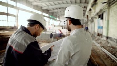 Müteahhit Çekme Makinası ile inşaat işçisi. Foreman ve yeni proje planı sitenin arka planı üzerinde çalıştığı Oluşturucusu arkadan görünüm.