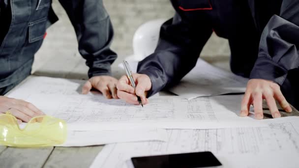 Upraw mężczyzn pracujących z blueprint. Przyciąć strzał bezimiennych mężczyzn pracujących przy stole z blueprint i współpraca. — Wideo stockowe