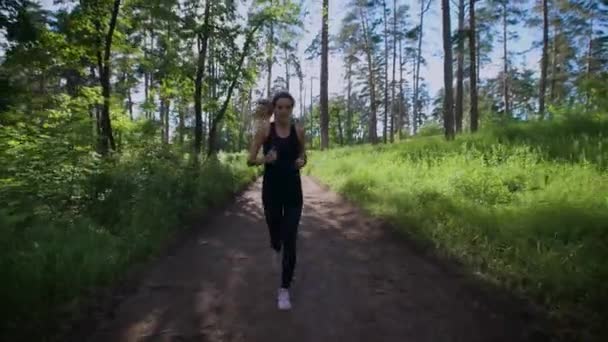 Dopasuj kobieta sportive jogging sam dół drogi w zielonym lesie — Wideo stockowe