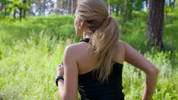 Спортивна жінка в спортивному одязі бігає сама в літньому красивому лісі — стокове відео