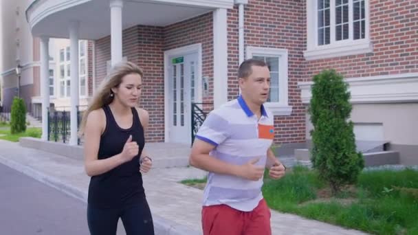 Молодой человек и женщина с решимостью бегут по городской улице — стоковое видео