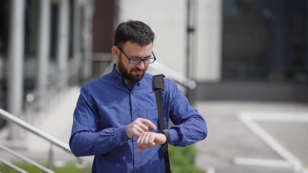 Affärsman härdningstid på klockor. Vuxen affärsman använder smart Watch-klocka eller ställa tiden stående på gatan. — Stockvideo