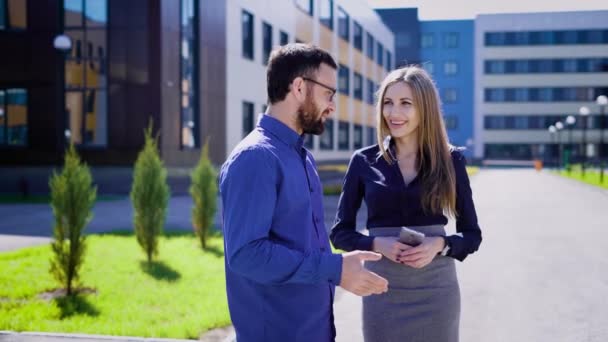 Zwei Unternehmer lächeln und reden. Männer und Frauen fröhliche Geschäftsleute kommunizieren und lächeln in Bürogebäude auf der Straße. — Stockvideo