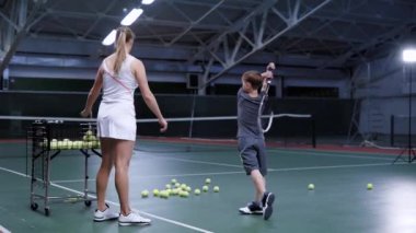 Küçük çocuk tenis oynamak eğitmektir güzel kadın tenis antrenörü