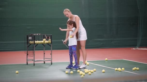 Mujer hermosa entrenador de tenis enseñando a la niña a jugar al tenis . — Vídeos de Stock