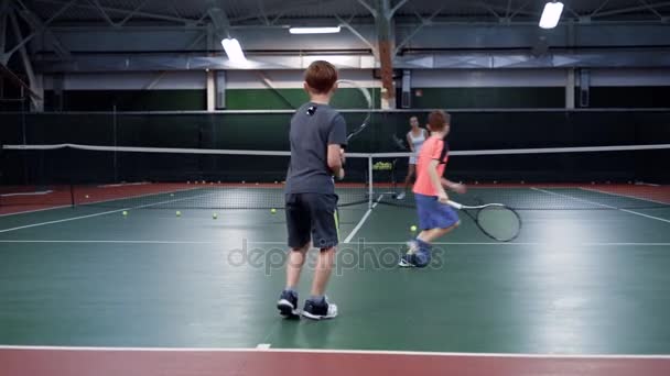 Team av två pojkar spelar tennis mot en mer äldre flicka eller tennis coach — Stockvideo