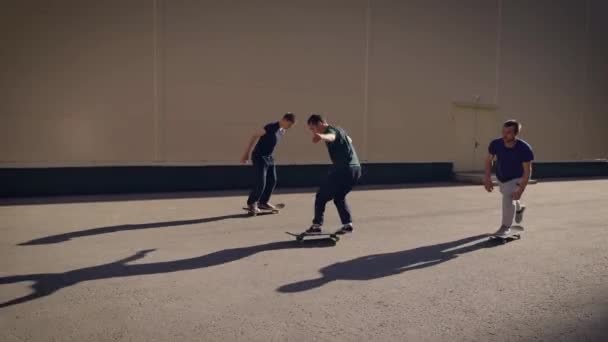 Конькобежцы катаются на скейтбордах возле промышленного здания в городе — стоковое видео
