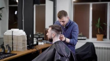 Salonda oturan istemciye şık saç yapma konsantre Kuaför adam