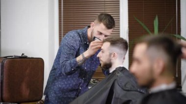 Konsantre Kuaför berber dükkanı istemciye şık saç modeli yaparken düzeltici kullanarak