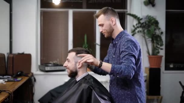 Friseur im Gespräch mit lächelnden Kunden bei der Herstellung stilvoller klassischer Frisur im Salon — Stockvideo