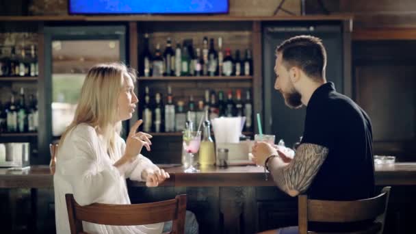 Genç erkek ve kadın arkadaş barda. Onlar konuşurken ve kokteyl içme. — Stok video