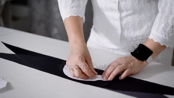 Женщина-портной делает узор на ткани, прикрепляя бумажный узор . — стоковое видео