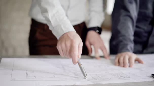 Close up van mannelijke handen van investeerder en opzichter bespreken bouw project tekeningen en specificaties. Architect en foreman werken samen aan het huidige project. — Stockvideo