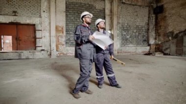 İki adam üniforma giymiş ve site oluşturma ve çalışma alanı üzerinde seyir Emanet kavganın ayakta duruyorlar. Foreman'ın Sarıyerde planı tutuyor. Oluşturucu ruh düzeyi tutuyor.