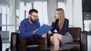 İş ortaklarını kanepede oturan ve arka planda windows ile iş merkezinde Toplantı mı. Kadın ve erkek meslektaşları konferans sırasında sorular görüşüyorlar.