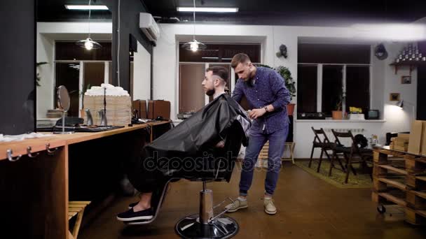 Criação de penteado elegante na barbearia. Cabeleireiro e cliente masculino. Vista do interior — Vídeo de Stock