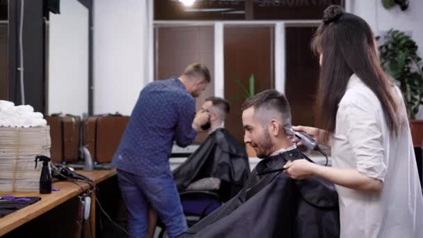 Kollektiv av frisörer på jobbet. Vy över scen av arbete på barbershop. Kunder som sitter på stolarna — Stockvideo