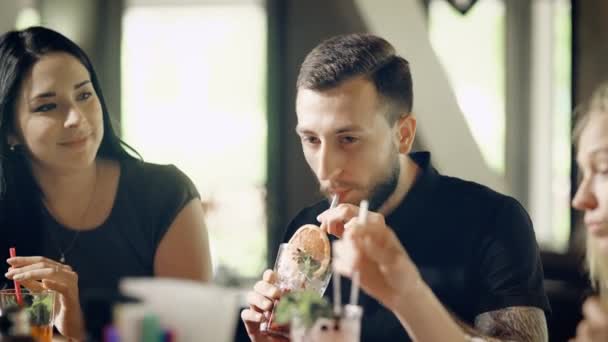 Los amigos felices beben bebidas alcohólicas largas en un bar o restaurante, los amigos se ríen, están felices de conocerse y hablar entre sí — Vídeo de stock